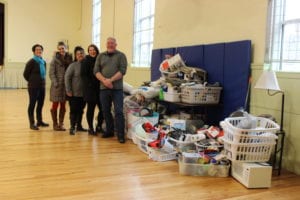 New Beginnings Staff and Androscoggin Staff stand next to the giant pile of donated items for the New Apartment kits. 