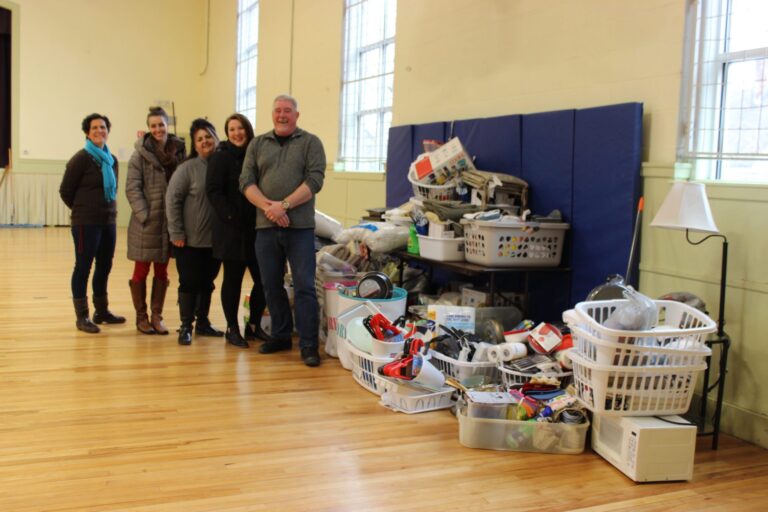 New Beginnings Staff and Androscoggin Staff stand next to the giant pile of donated items for the New Apartment kits.